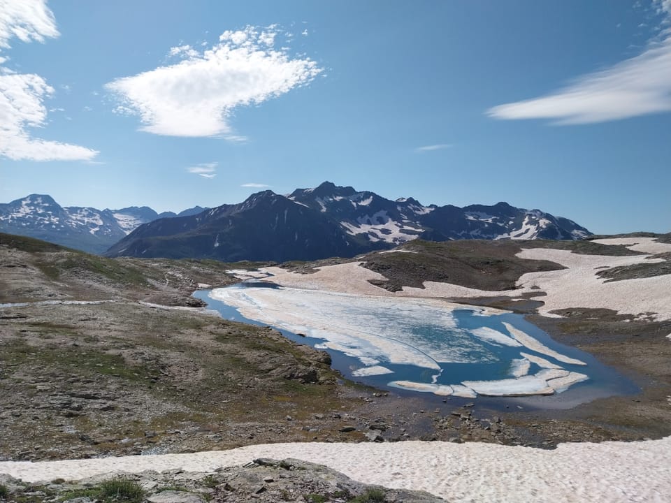 Wunderschöne Gebirgslandschaft mit Bergsee inklusive schwimmendem Eis und Altschnee.