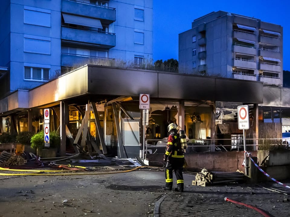 Feuerwehrmann vor zerstörtem Gebäude in der Stadt bei Nacht.