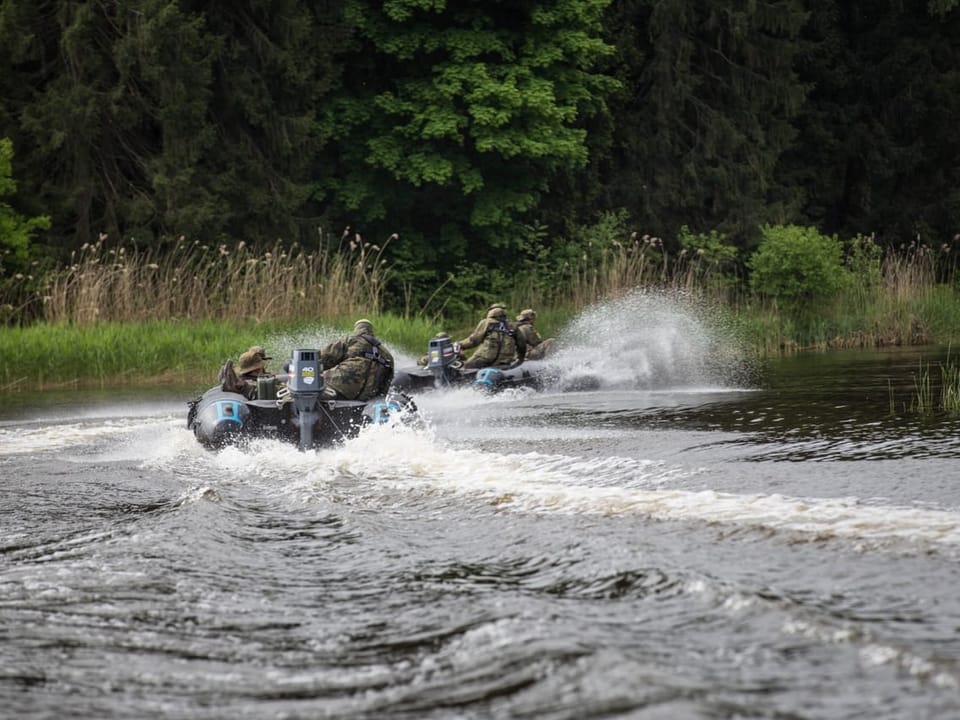 Militärische Schlauchboote fahren auf einem Fluss.
