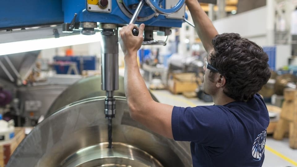 Ein Mann baut in einer Produktionshalle Teile für einen Dieselmotor zusammen.