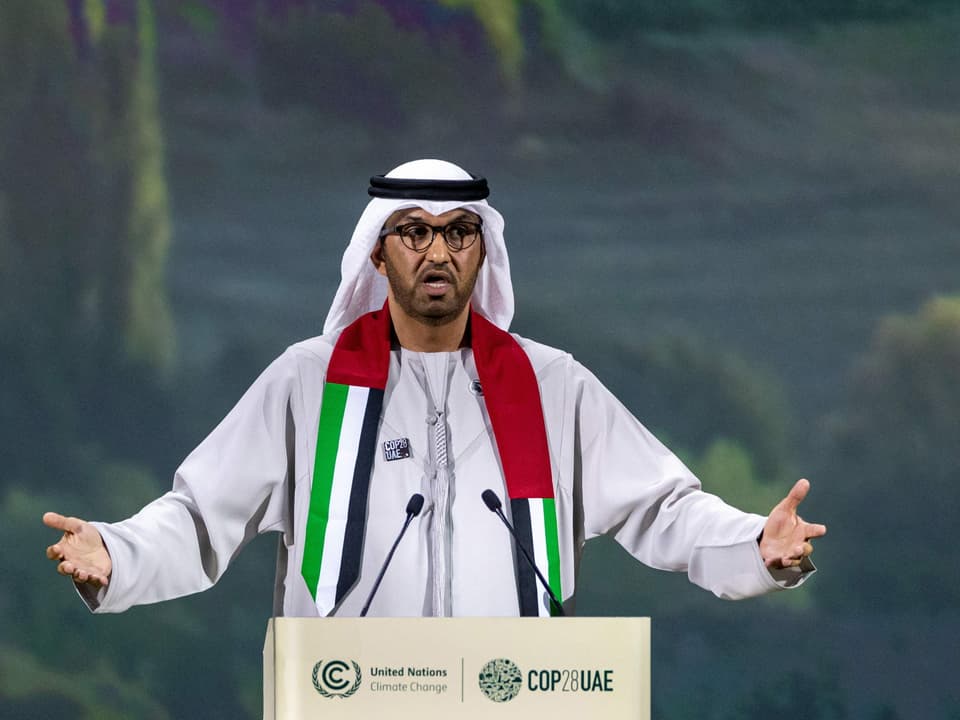 Ahmed Al Dschaber gestikuliert am REdnerpult, er hat einen Schal mit den Landesfarben der Vereinigten Arabischen Emirate umgehängt