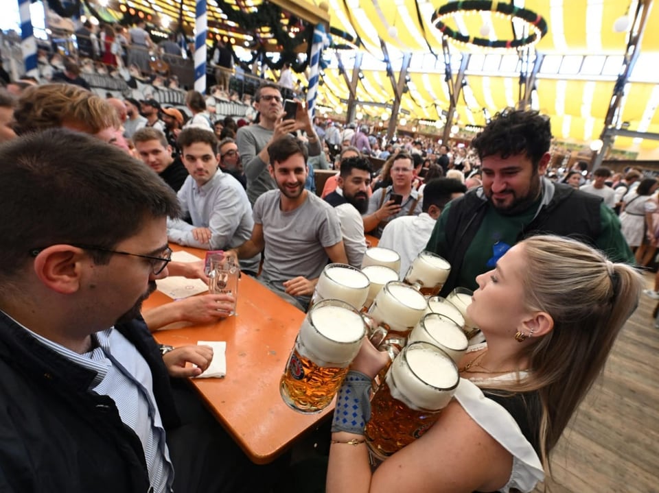 Kellnerin serviert Bierkrüge in einem vollen Festzelt.