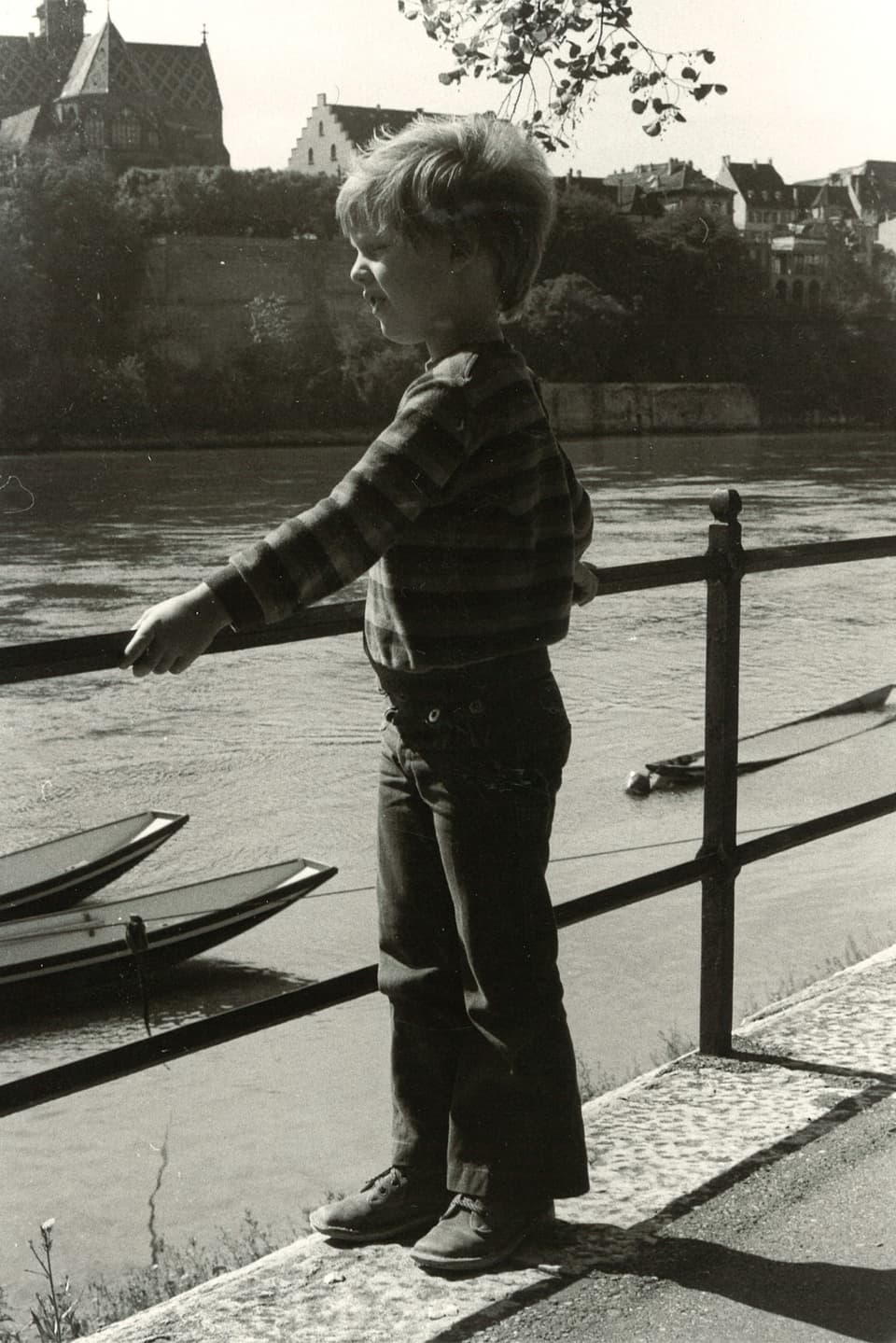 Kleiner Junge betrachtet Kanus auf dem Rhein.