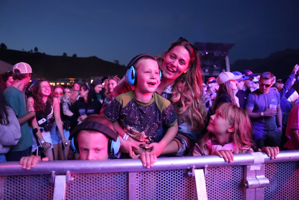 Menschenmenge bei einem Konzert, Frau mit zwei Kindern an der Absperrung am Open Air Lumnezia 2024..