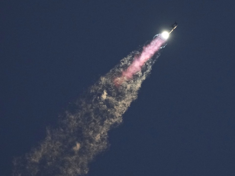 Rakete startet in den Nachthimmel mit Rauchspur.