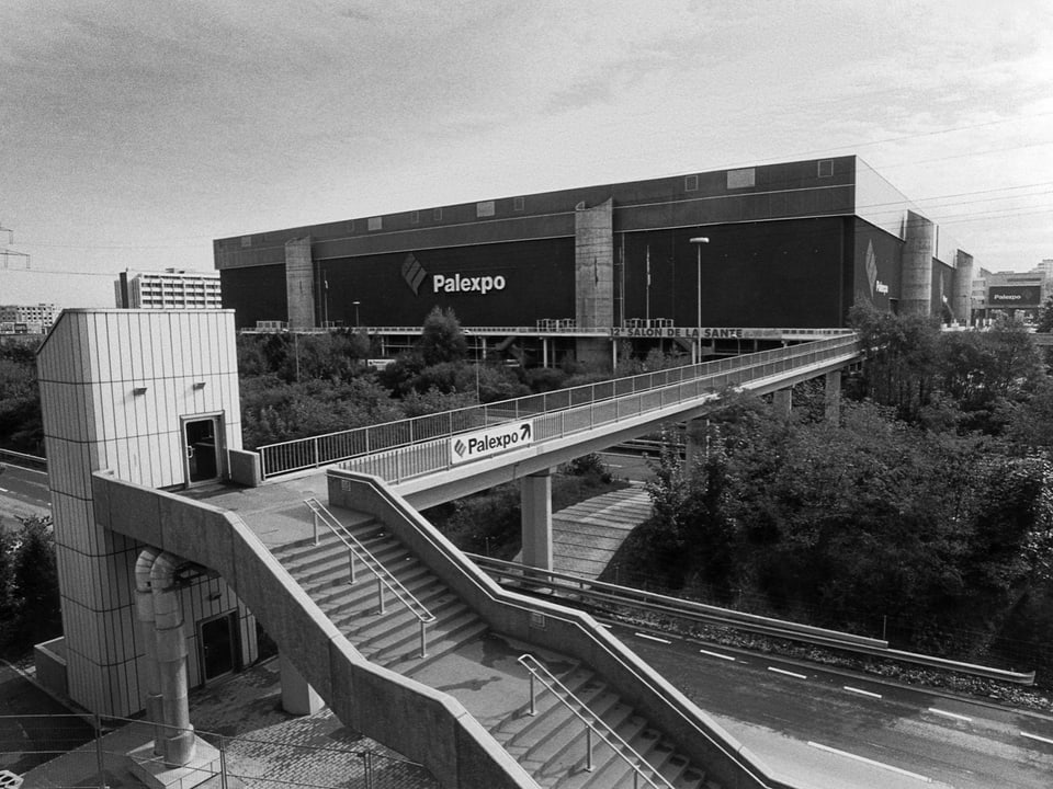 Schwarzweissfoto von Palexpo-Gebäude mit Fussgängerbrücke und Treppe.