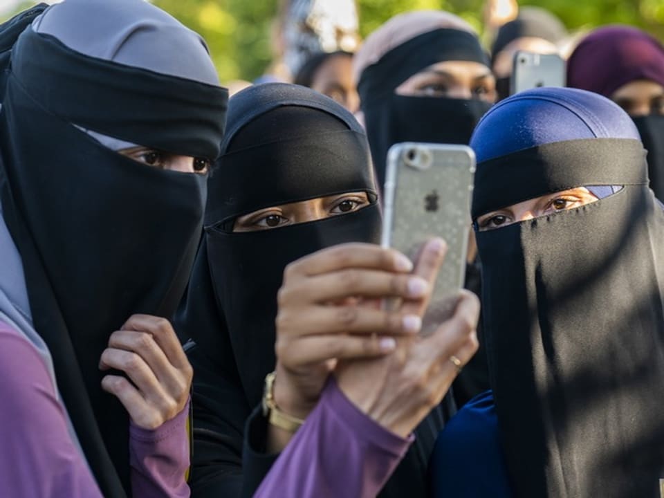 Mehrere Menschen in Hijab machen ein Selfie mit einem Smartphone.