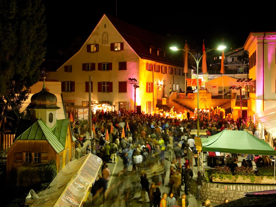 Nächtliche Stimmung mit vielen Menschen, die im Dorf unterwegs sind.