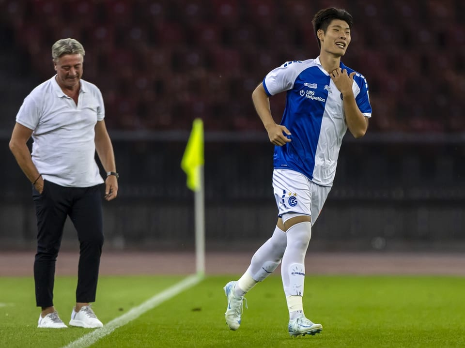 Fussballspieler auf dem Spielfeld neben Trainer.