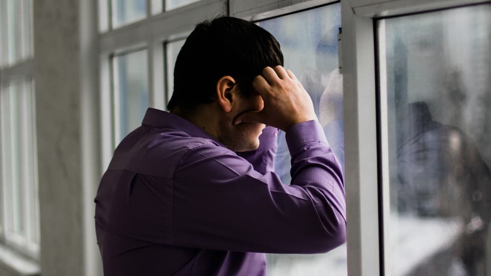 Mann stützt sich an Fenster.