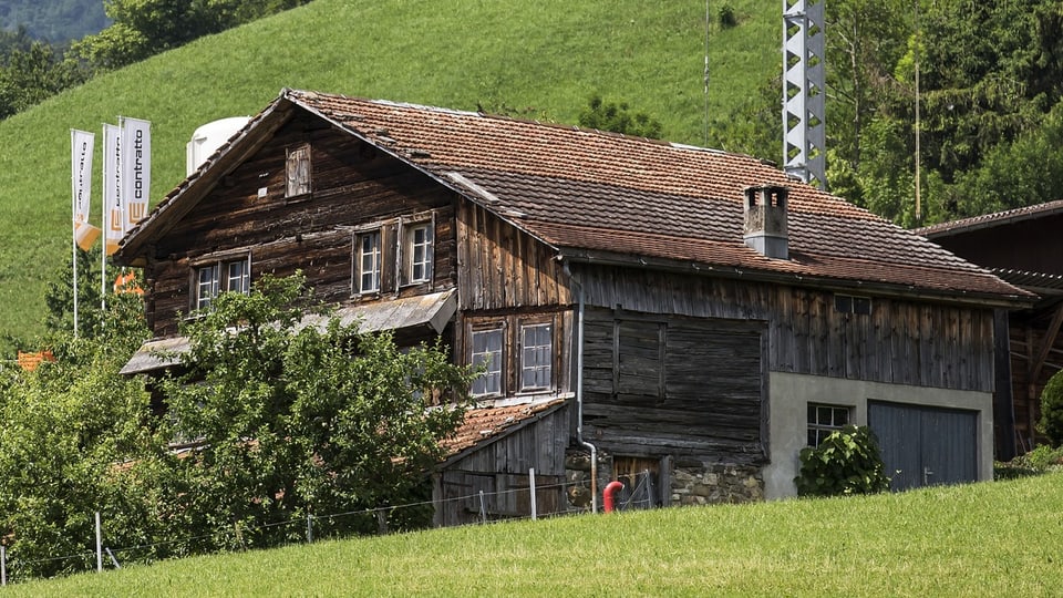 Auf dem Bild ist ein Holzhaus mit ganz dunkler Fassade zu sehen.