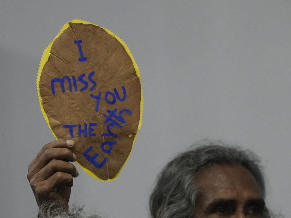 Person hält Schild mit Aufschrift 'I miss you the Earth'.