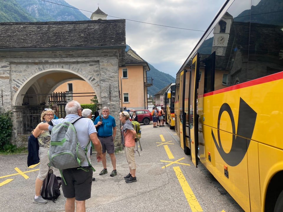 Gruppe von Menschen steht neben einem gelben Bus.