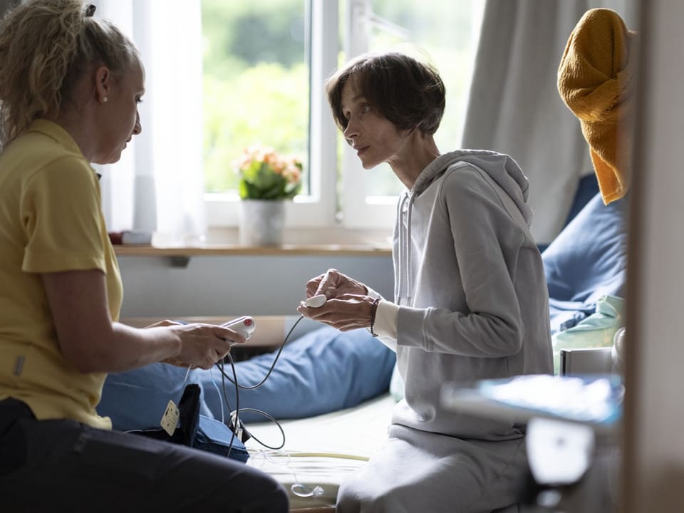 In einem Pflegezentrum wird einer schwerkranken Patientin auf der Palliativstation eine Medikamentenpumpe erklärt. 