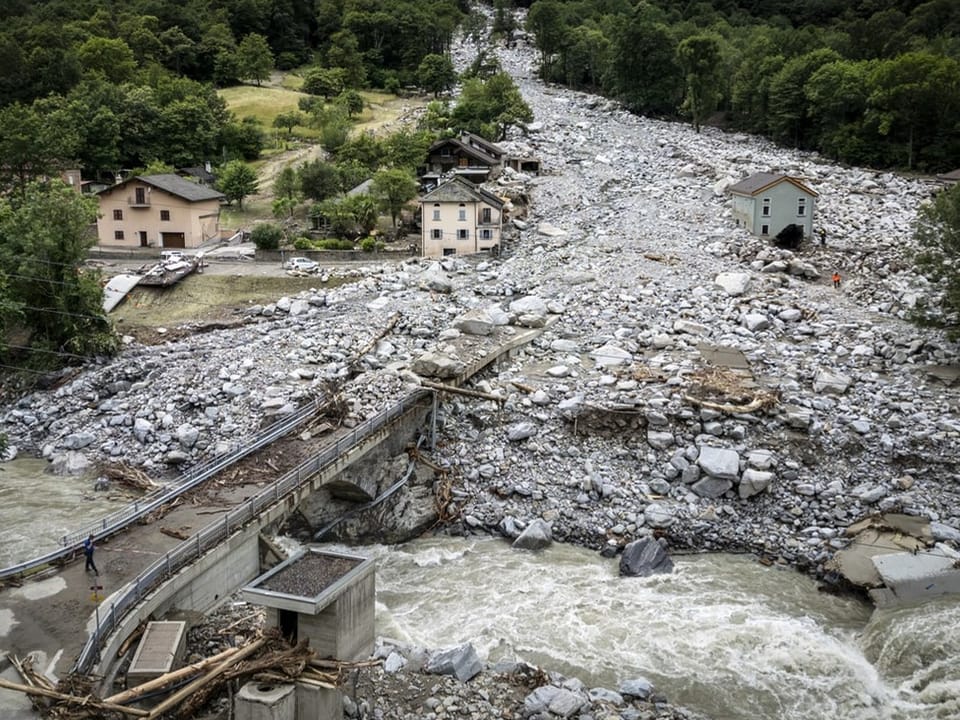 Luftaufnahme einer von Erdrutschen verwüsteten Landschaft mit zerstörten Gebäuden.