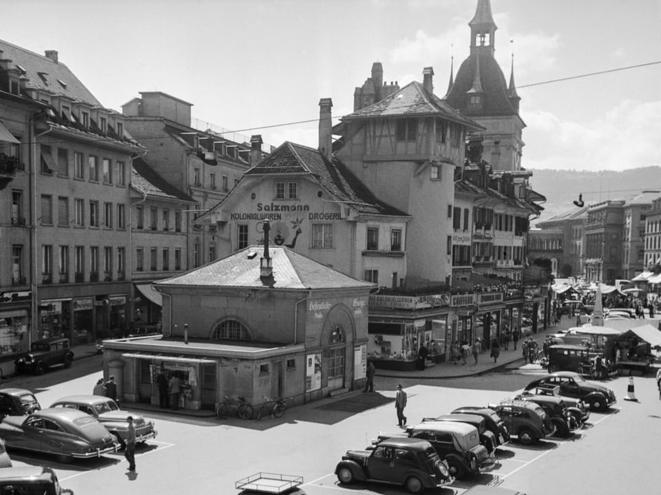 Historischer Marktplatz mit alten Autos und Gebäuden.