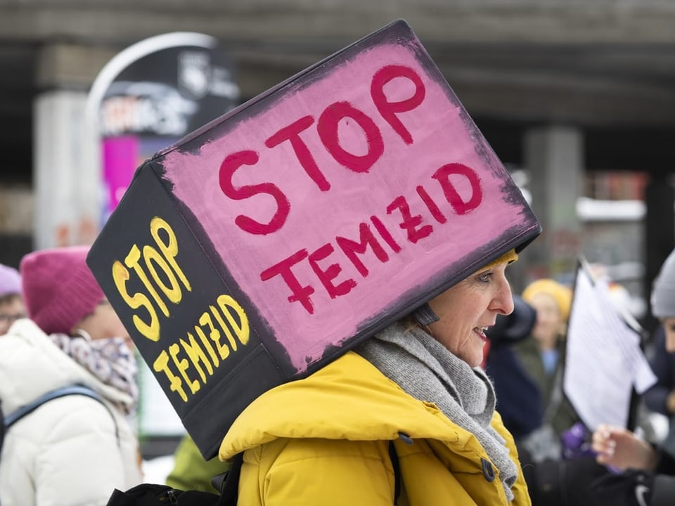 Person mit Schild 'Stop Femizid' bei einer Demonstration.