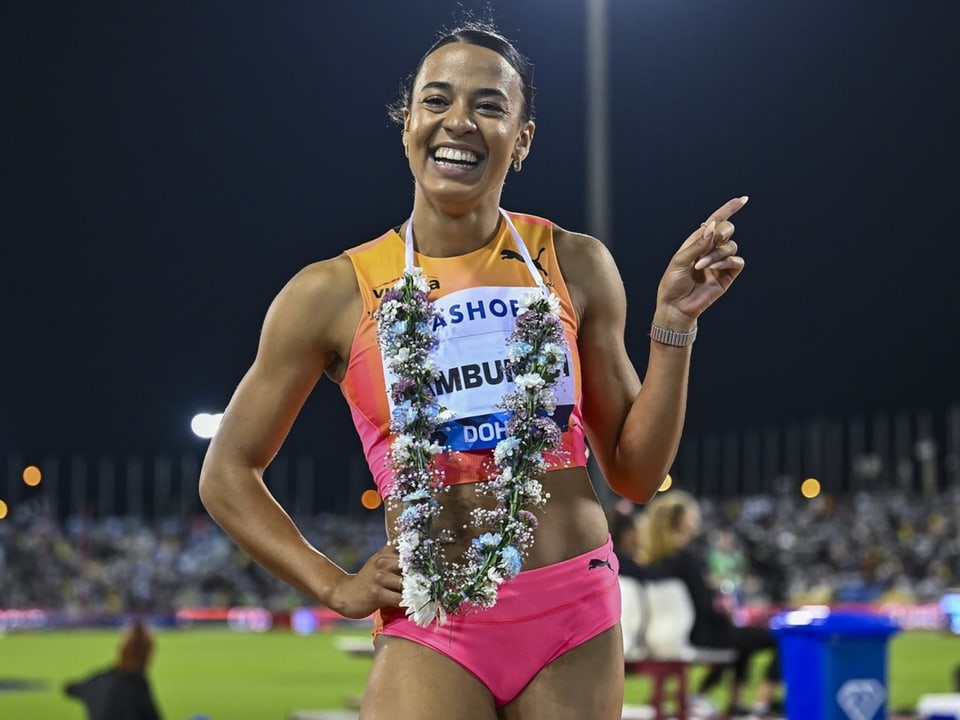 Lächelnde Sportlerin in pinkem Outfit bei Nacht, trägt Blumenkranz.