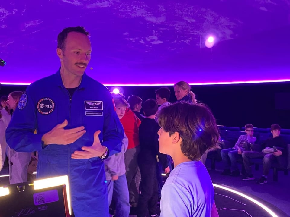 Ein Astronaut spricht mit einem Kind in einem futuristischen Raum.