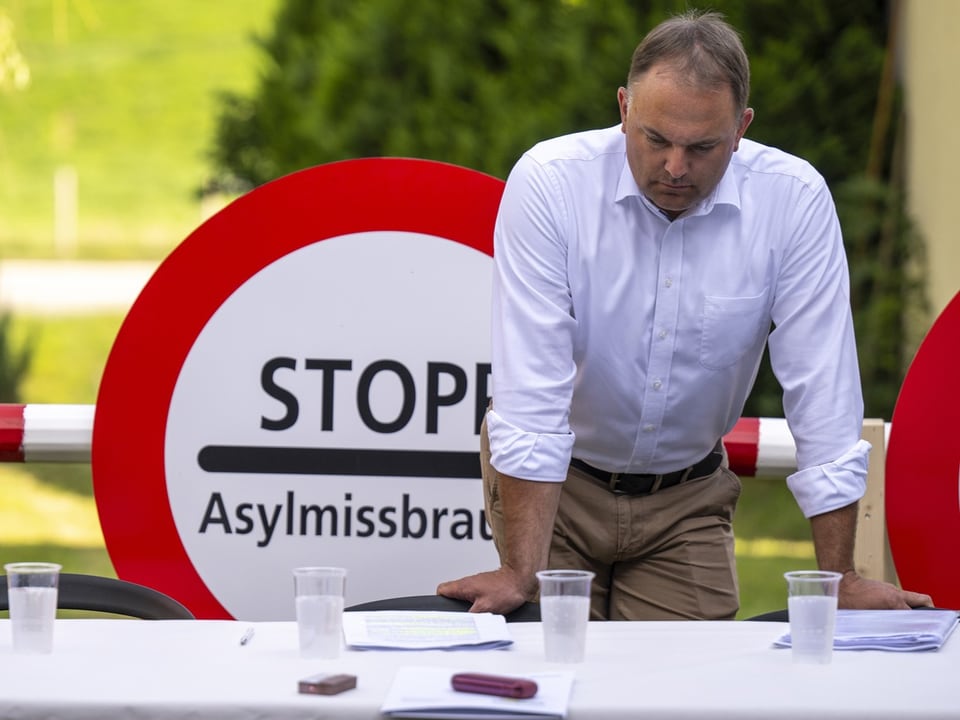 Mann steht vor Plakat 'Stopp Asylmissbrauch'