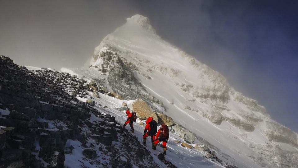 Drei Bergsteiger im Augstieg zum Gipfel