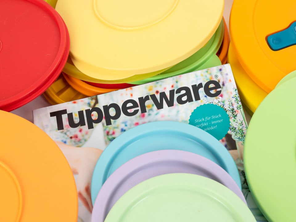 Tupperware-Deckel in verschiedenen Farben auf einem Katalog.