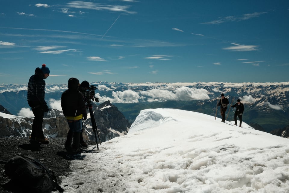 Ein Filmteam filmt Kletterer auf einem schneebedeckten Berggipfel.