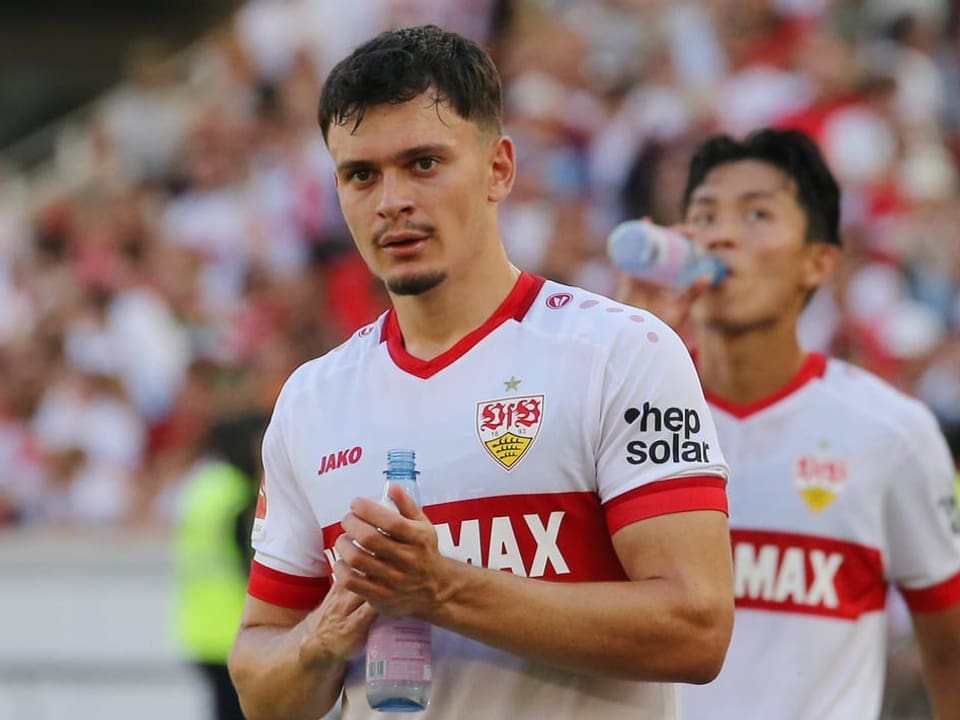 Fussballspieler im weissen Trikot mit rotem Streifen hält eine Wasserflasche.