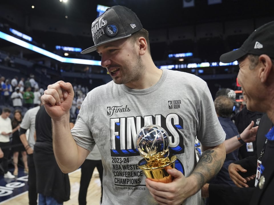 Basketballspieler feiert mit Trophäe.