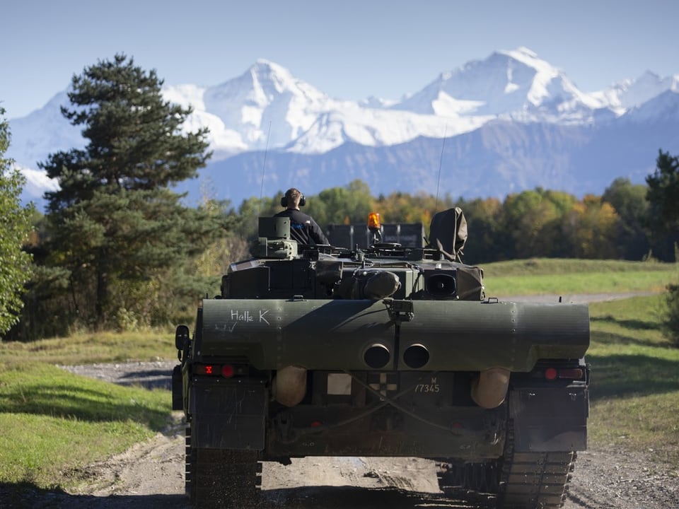 Panzer fährt auf auf einer Landstrasse vor den schneebedeckten Berner Alpen.