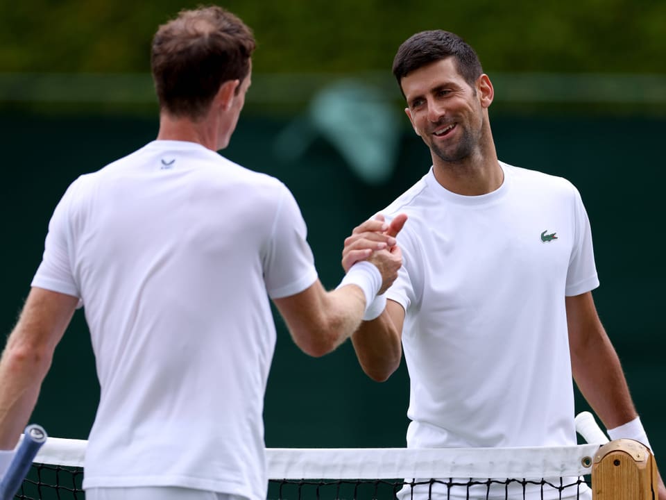 Zwei Tennisspieler schütteln sich die Hand über dem Netz.