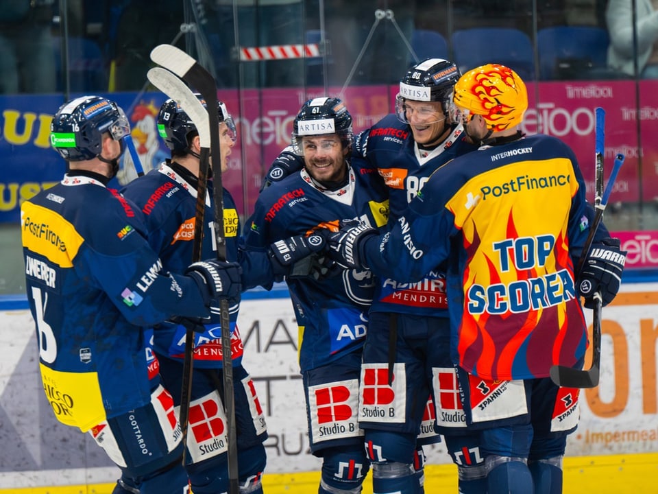 Eishockeyspieler feiern auf dem Eis, einer trägt einen 'Top Scorer'-Helm.