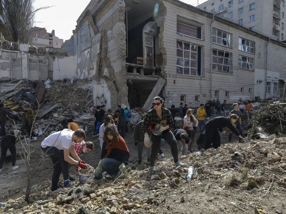 Studenten beseitigen die Trümmer einer Universität in Kiew, nachdem diese durch einen Raketeneinschlag beschädigt wurde.