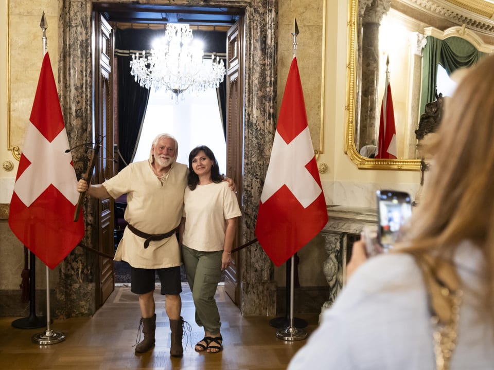 Zwei Personen posieren zwischen zwei Schweizer Flaggen.