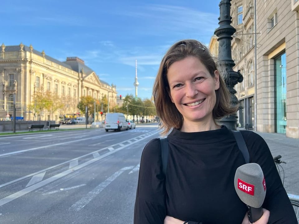 Deutschland-Korrespondentin Simone Fatzer steht in einer Strasse in Berlin mit dem Mikrofon in der Hand.
