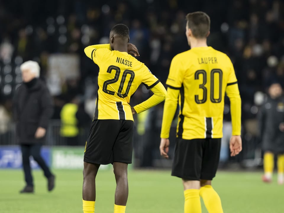 Zwei Fussballspieler in gelben Trikots auf dem Spielfeld.