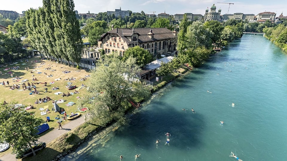 Bern: im Hintergrund das Bundeshaus, im Vordergrund die Aare mit schwimmenden Leuten.