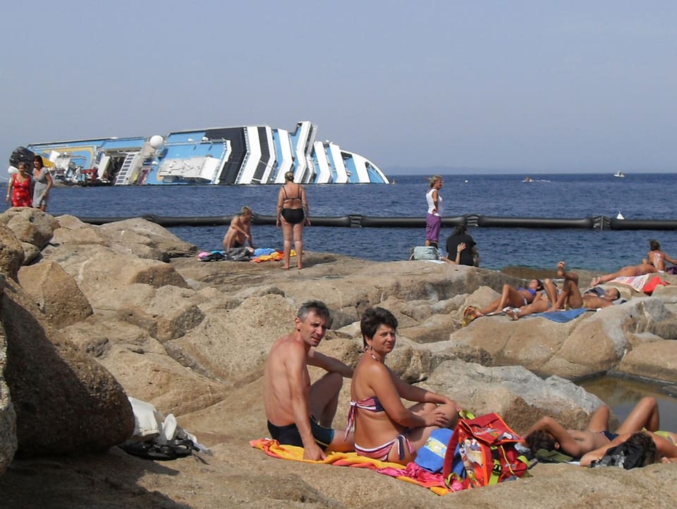 Menschen in Badehosen am Strand.