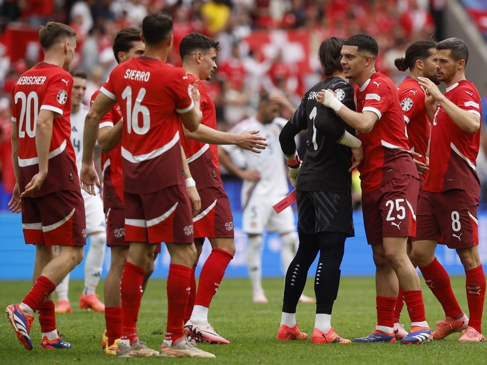 Fussballmannschaft in roten Trikots feiert auf dem Spielfeld.