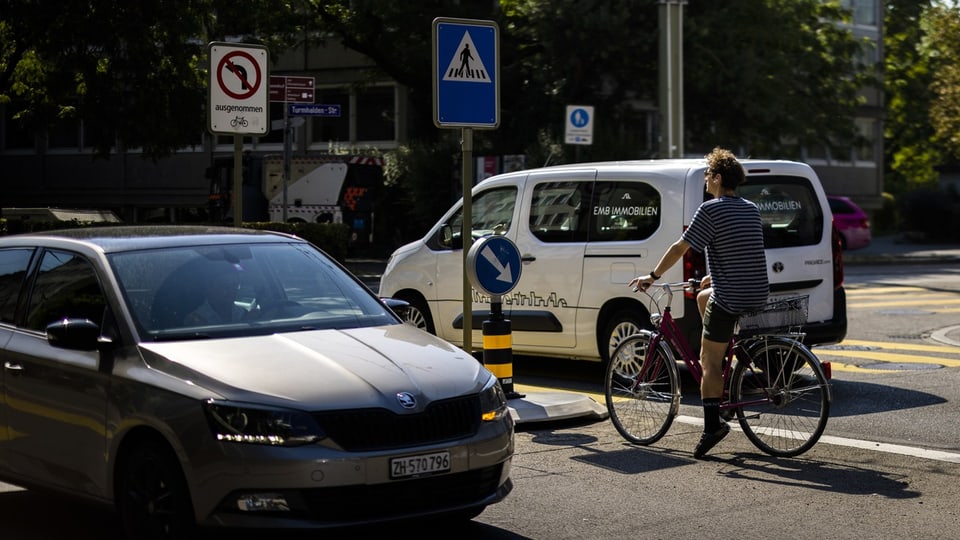 Auto und Fahrradfahrer an einer Kreuzung in der Stadt.
