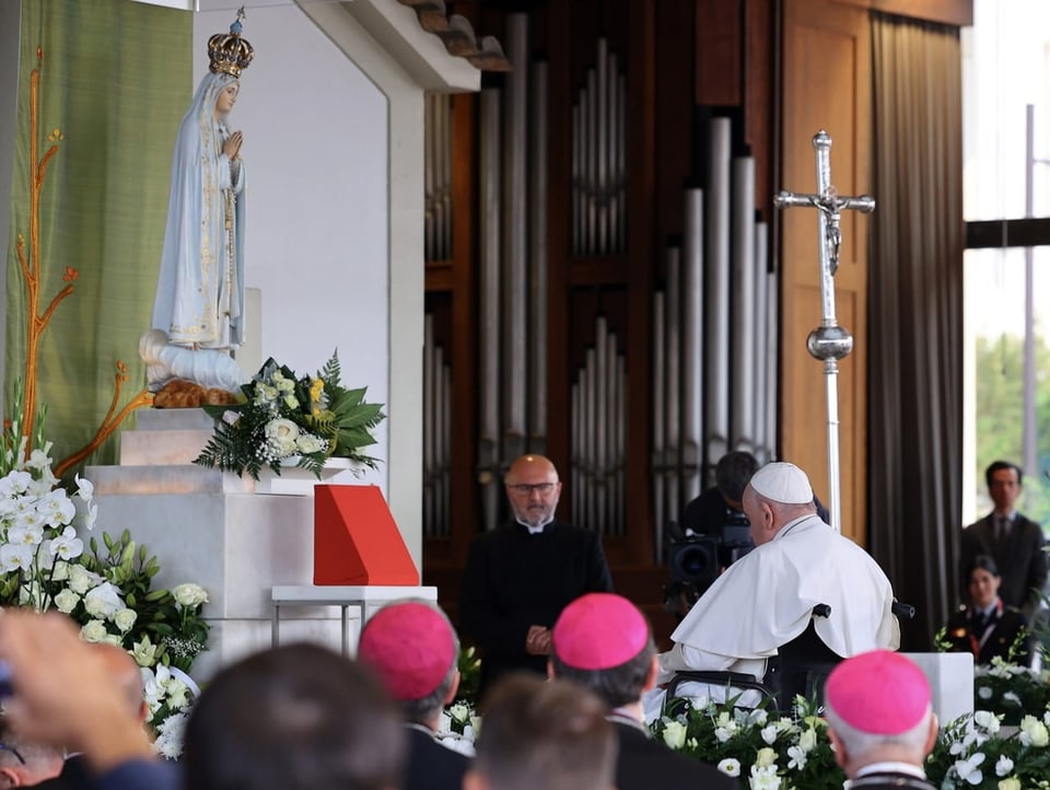 Der Papst sitzt vor der weissen Statue, die etwa Kinder-gross ist.