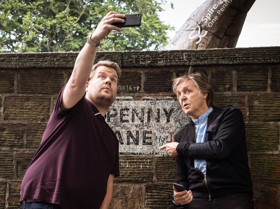 Paul McCartney und James Corden stehen vor einer Wand mit dem Schriftzug Penny Lane. McCartney hat sie unterschrieben.