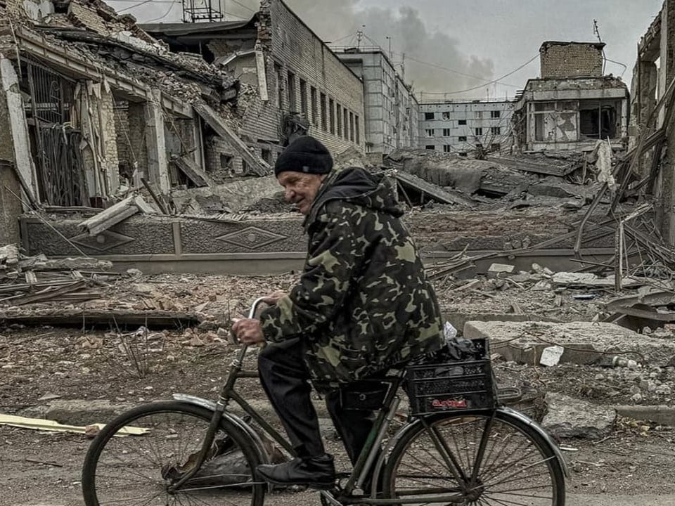 Ein Mann fährt mit seinem Fahrrad am durch russische Luftschläge zerstörten Postgebäude von Kurachowe vorbei.