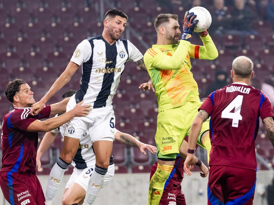 Fussballspieler im Sprung, Torwart fängt den Ball.