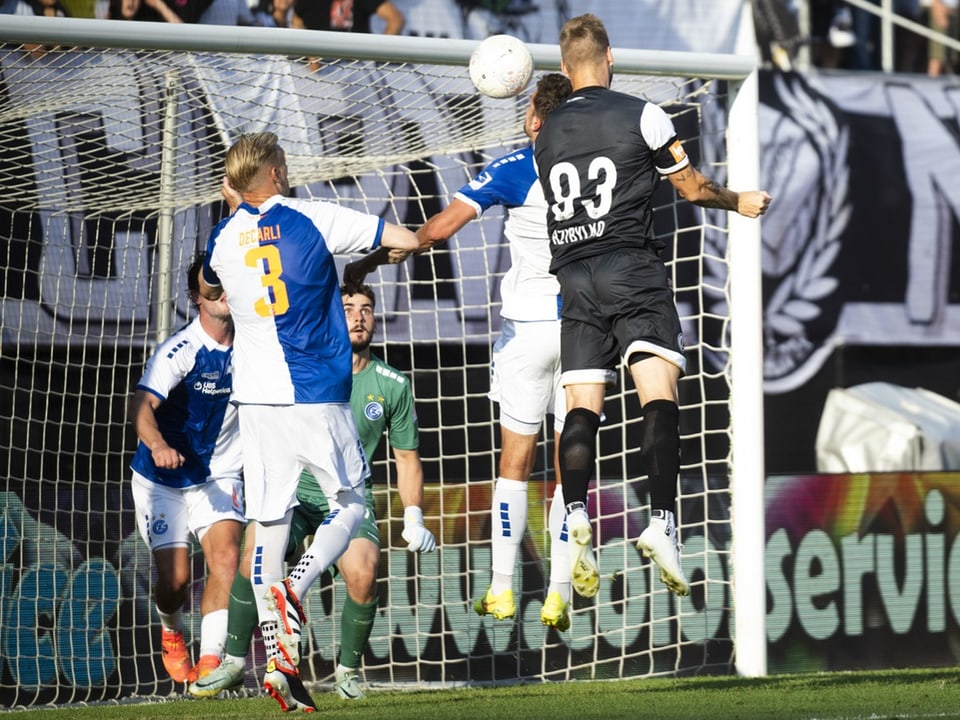 Fussballspiel, Spieler springen nach dem Ball vor dem Tor.