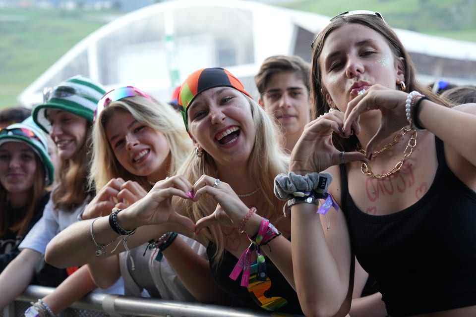 Gruppe von jungen Leuten auf einem Konzert, die Herzformen mit ihren Händen machen am Open Air Lumnezia 2024.