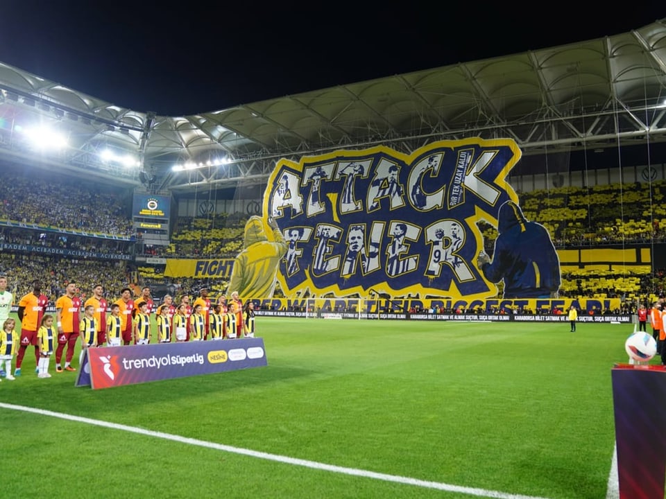 Fussballstadion mit grosser 'Attack Tiger'-Choreografie und Mannschaften vor dem Spiel.