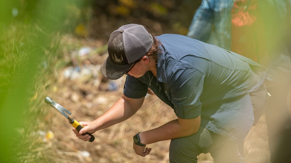 Eine Person untersucht den Boden mit einem Hammer.