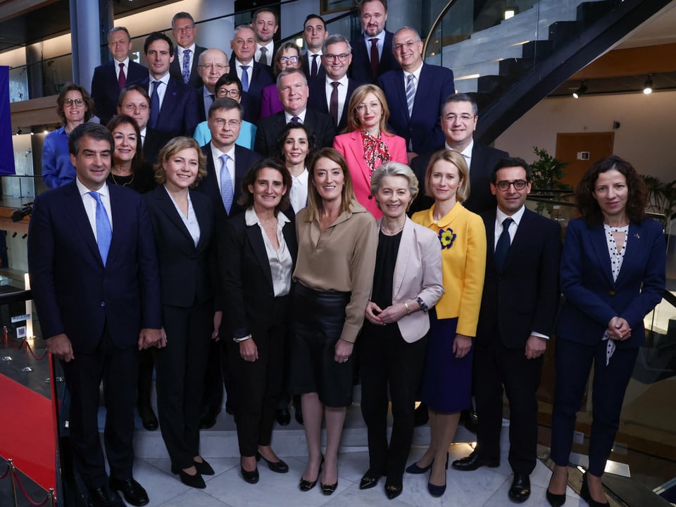 Gruppe von Menschen in formeller Kleidung auf einer Treppe.