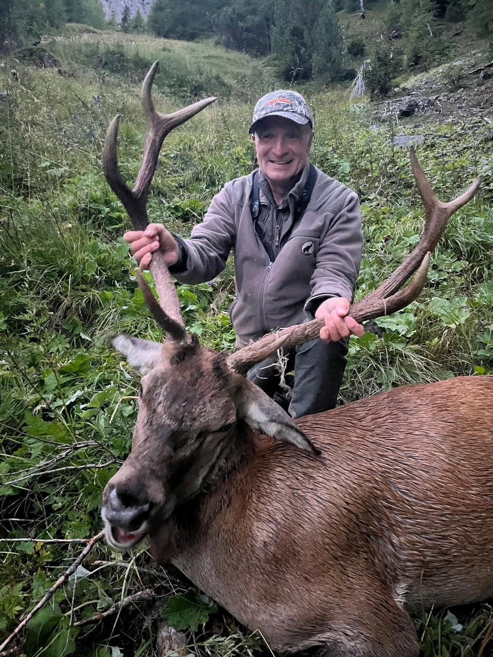 Mann hält Geweih eines erlegten Hirsches im Wald.